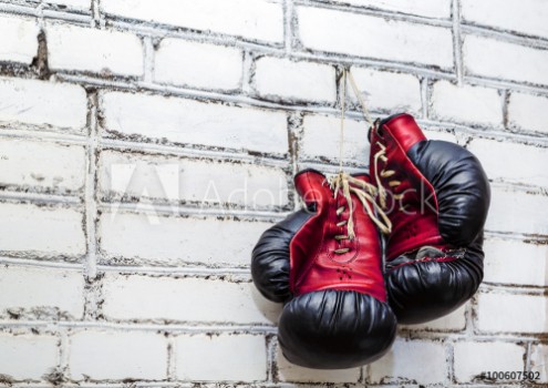 Picture of A pair of old boxing gloves hanging on white brick wall background